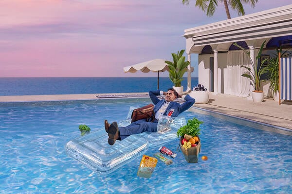 Man sitting in a pool on a floatation device with Velocity rewards floating in the water 