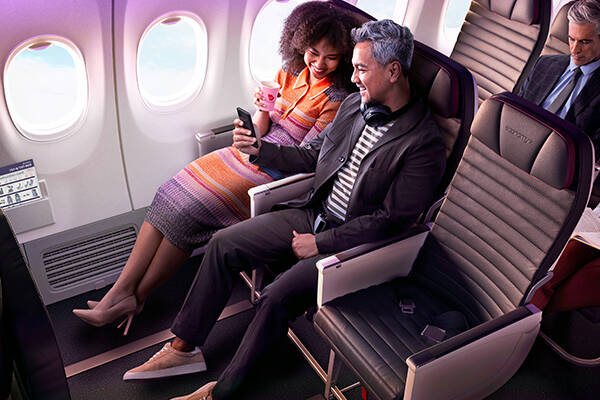 A couple sitting next to each other laughing, whilst sitting in airplane seats