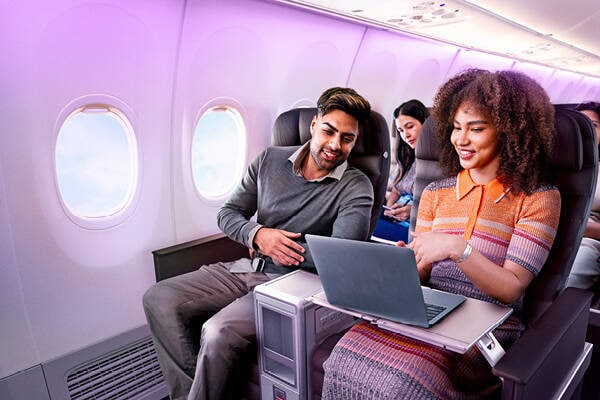 A couple sitting next to each other laughing, whilst sitting in airplane seats