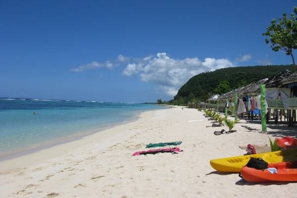 Kayaks on bright sunny beach overlooking water in Samoa