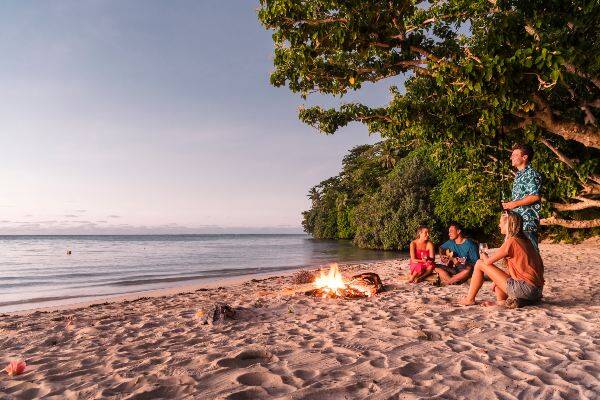 Friends enjoying a sunset bonfire on the beach in Samoa