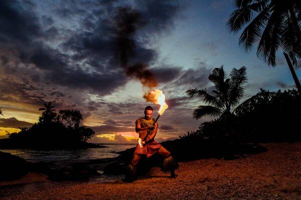 Samoan local performing fire dance on beach during sunset
