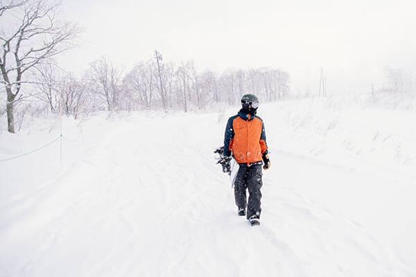 Person in Orange holding snowboard in Hukuba ski field.