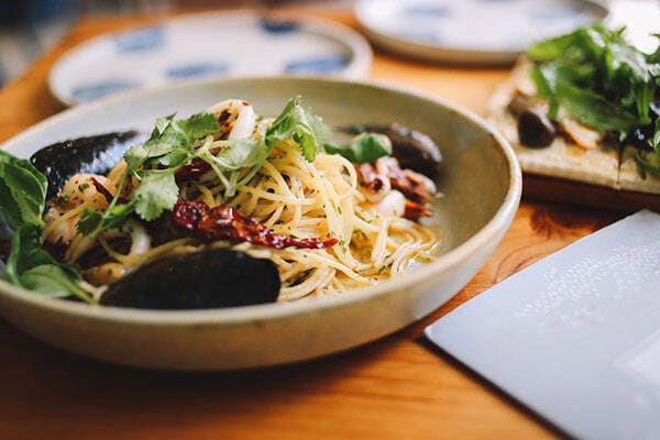 bowl of pasta and menu on table