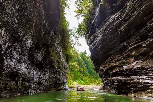 A group paddles through the Upper Navua River in a boat, surrounded by stunning rock formations and beautiful natural scenery.