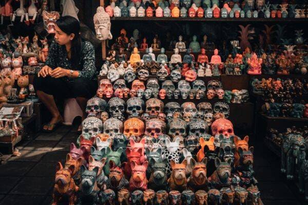 Woman sitting beside calavera sculptures at Ubud Art Market