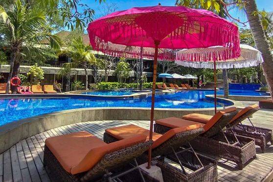 Sun lounges under umbrella at resort pool at Aston Sunset Beach Resort Gili Trawangan, Bali