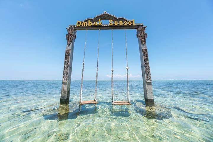 Famous swing in clear blue water on island at Gili Trawangan, Bali