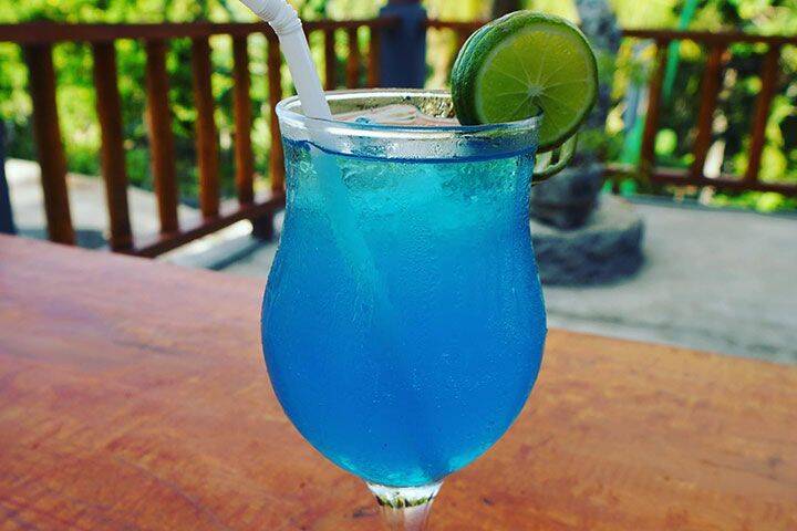 Bright blue cocktail with lime wedge on glass served at Kelingking Ba Restaraunt Nusa Penida, Bali
