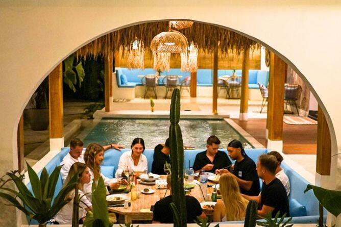 Group of diners enjoying a meal at table behind water feature at The Rich restaurant Nusa Penida, Bali
