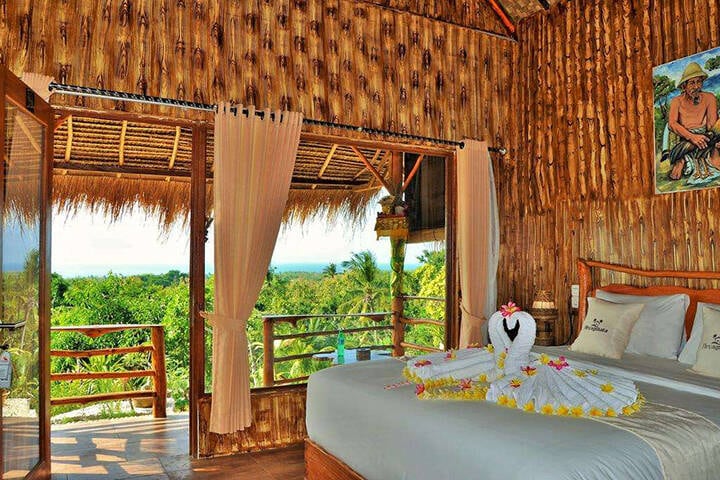 Master bedroom suite facing green trees outside balcony at Aryaginata Cliff Cottages Nusa Penida, Bali