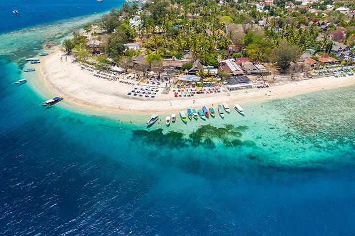 Aerial view of boats moored off a beautiful tropical coral reef and beach on a small island (Gili Air, Indonesia)