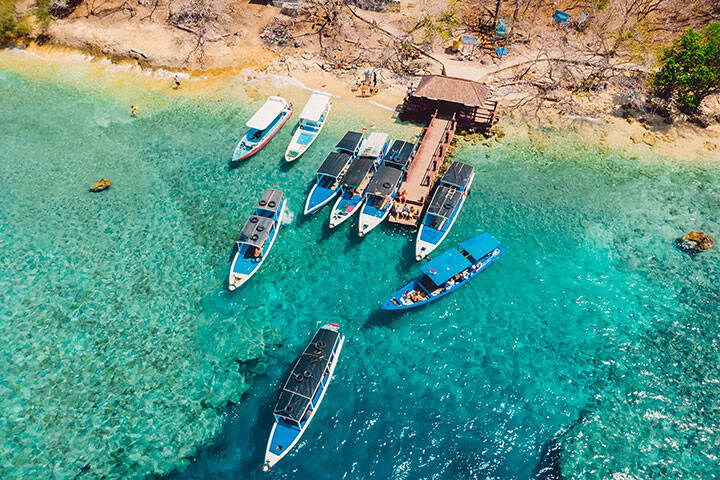 Touristic boats near the pier in transparent ocean at Menjangan island. Aerial view.