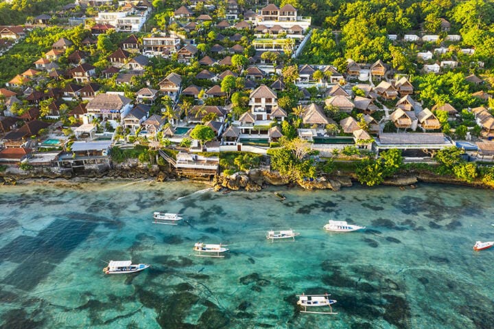 Aerial view of luxury villa and hotels on the Nusa Lembongan island coast facing the turquoise colored sea in Bali, Indonesia