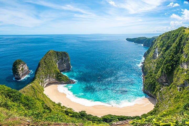 Aerial photo of green island and calm water at Kelingking beach in Nusa Penida