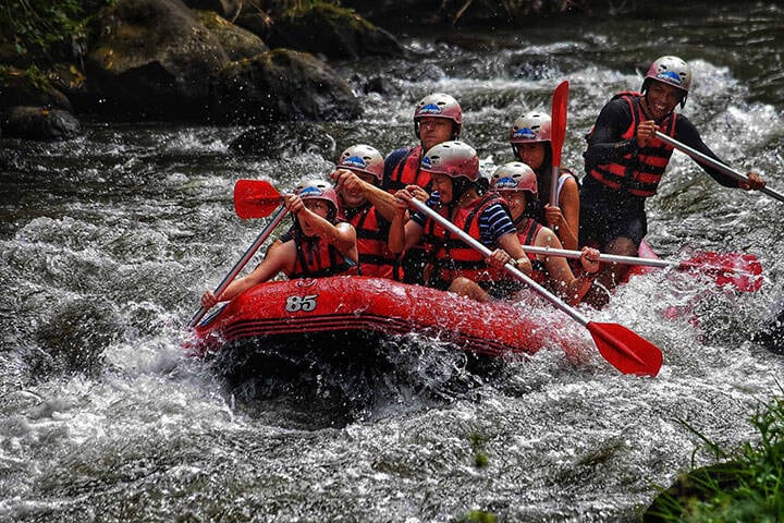 Tourists and a guide in a red raft on the rapids of the Ayung River near Ubud