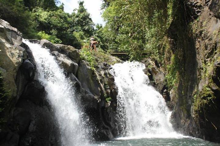 Two streams of water gushing down onto rocks at Air Terjun Sambangan Waterfall, Bali