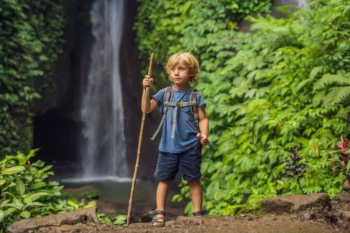 Toddler holding stick ready to explore rainforest at Jagasatru Waterfall, Bali