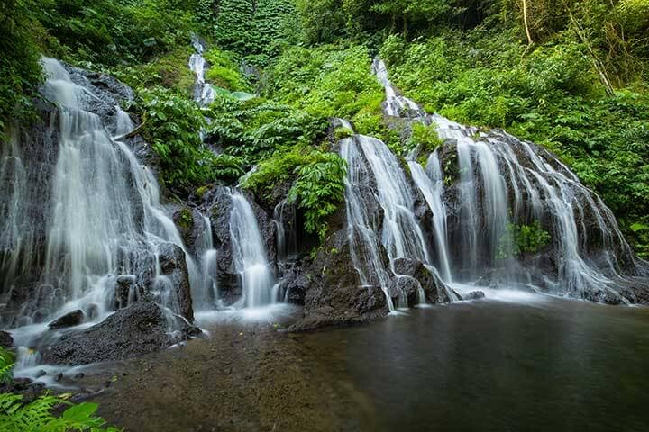 Water flowing through greenery into watering hole at Pucak Manik Waterfall, Bali