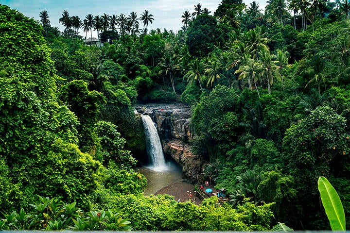 Travellers playing on rocks at Tegenungan Waterfall, Bali