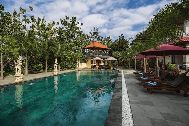 Outdoor lounges and swimming pool facing lush green trees at House of Om Ubud, Bali