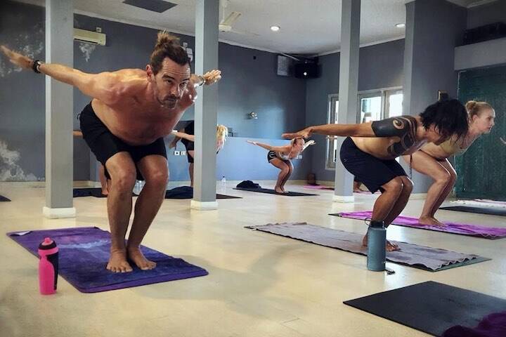 Men and women in lunge pose sweating inside indoor studio at Jiwa Bikram Yoga Seminyak, Bali