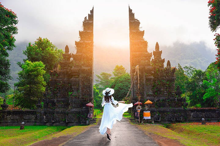 Woman wearing a loose dress, hat, and sandals for Bali's hot, humid weather