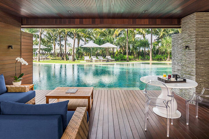 Private rooms overlooking blue swimming pool at COMO Uma Canggu, Bali