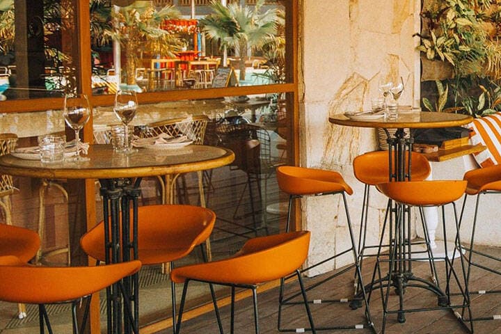 Outdoor seating area with bar stools and tables beach at El Bazar Restaurant at Origin Lombok 