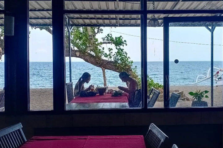 Outdoor dining area with chairs and tables along middle at Warung Menega, Lombok