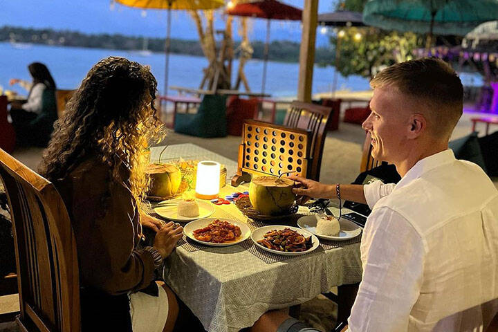 Couple enjoying candlelit dinner overlooking water at Yoman Café at Sira Beach, Lombok