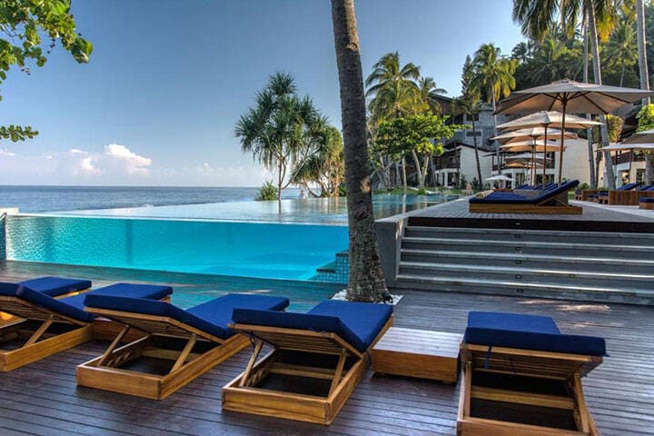 Sun lounges lined up on deck overlooking swimming pool at Katamaran Resort, West Lombok