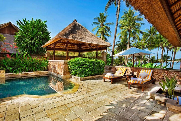 Outdoor pool area with lounges and sun hut at The Oberoi, North Lombok