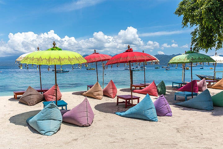 Colourful umbrellas, bean bag chairs, and the beautiful ocean coast of Gili Trawangan Island, Bali, Indonesia