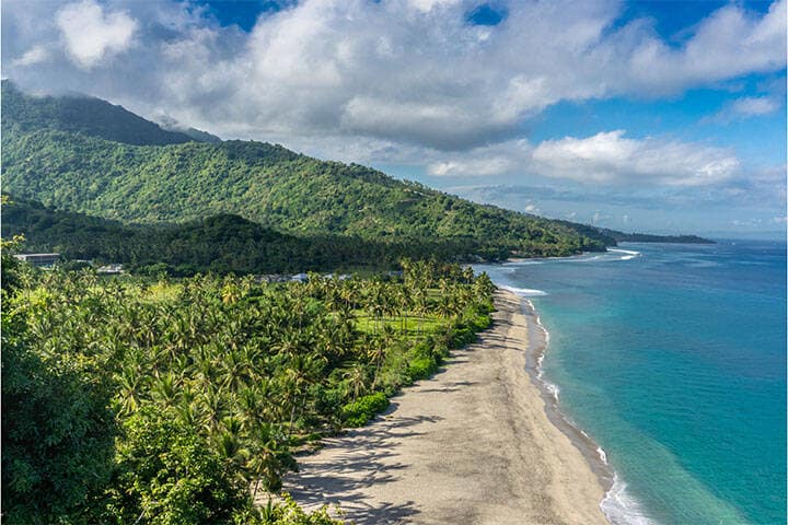 Aerial view of the ocean, shore and tropical palm trees at Senggigi Beach in West Lombok, Indonesia