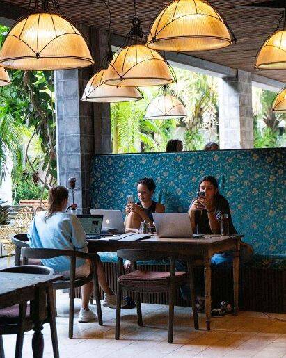 Travellers eating breakfast while working on laptops on dining table at Bittersweet Cafe Ubud, Bali