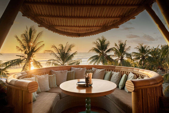 Private lounge balcony overlooking beach waves during sunset at Azul Beach Club, Bali