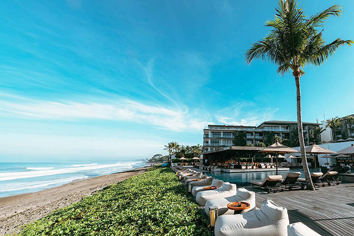 Lounges on beach overlooking waves at Alila Seminyak