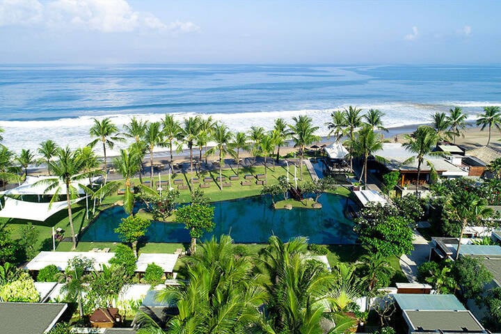 Aerial view of swimming pool and lush greenery overlooking ocean at Samaya Seminyak Resort