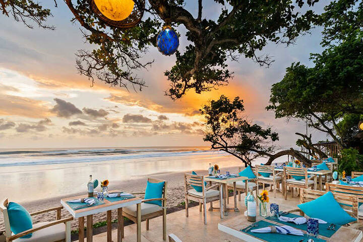 Dining tables and sun lounges on the sand at The Seminyak Beach Resort & Spa