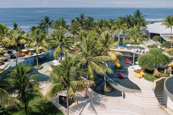 A luxurious view of W Bali in Seminyak, showcasing stylish accommodations surrounded by lush tropical landscaping. The vibrant atmosphere features sleek architecture and inviting outdoor spaces, highlighting the resort's blend of modern comfort and Balinese charm.