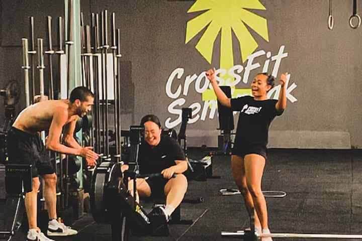 Trainers cheering on athlete on rowing machine at gym in Crossfit Seminyak, Bali