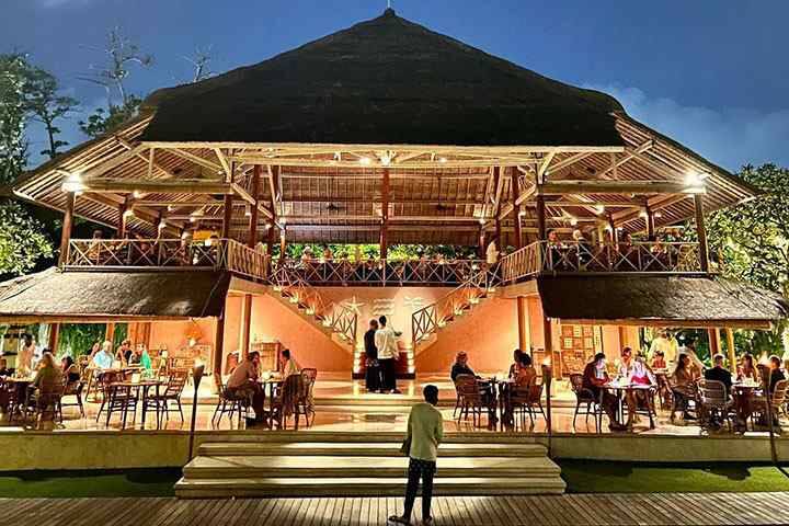 Outdoor dining tables underneath deck with mood lighting at La Lucciola Restaurant Seminyak, Bali