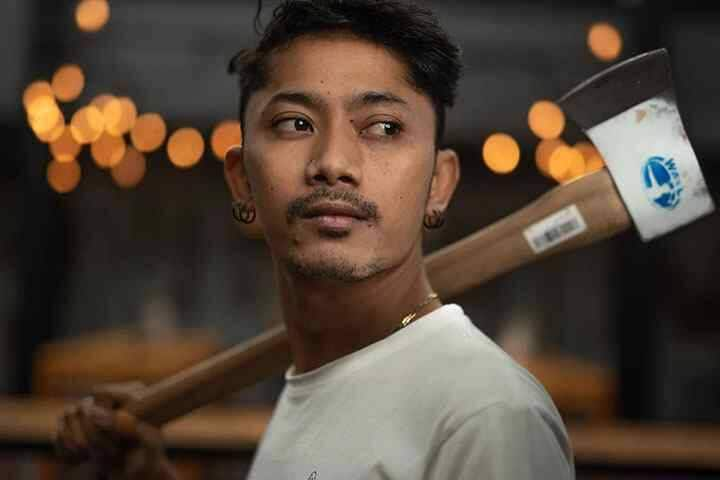 Man with axe thrown over shoulder looking at wood target at Motherhuckers Seminyak, Bali