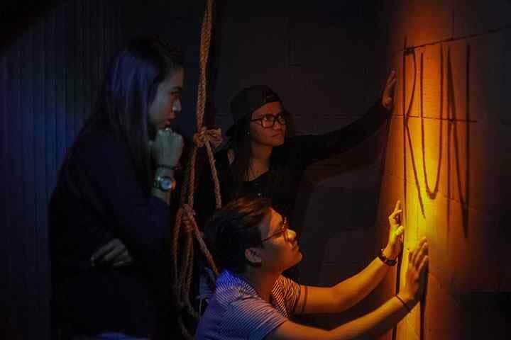 Group looking for clues on wall at Pandora Experience Escape Room Seminyak, Bali