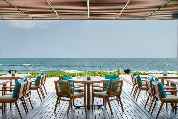 Outdoor dining tables on deck overlooking beach at Seasalt Restaurant Seminyak, Bali