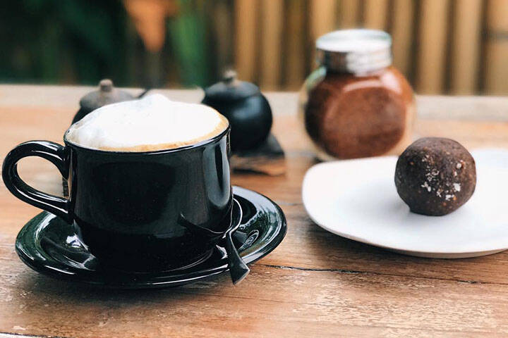 Cappuccino and protein ball served on dining table at Land End Cafe Uluwatu, Bali