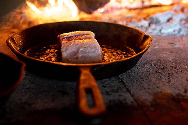 Food being cooked in cast iron pan over hot grill at M Mason Bar Grill Uluwatu, Bali