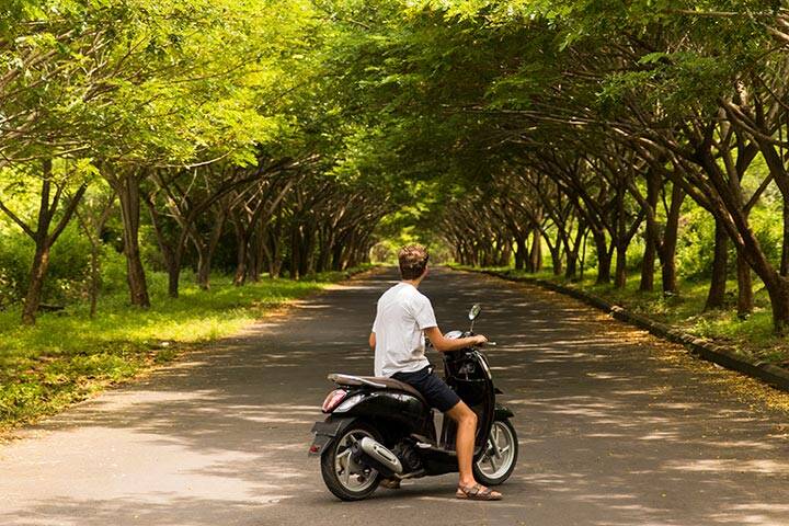 Man on scooter riding through road in Uluwatu, Bali