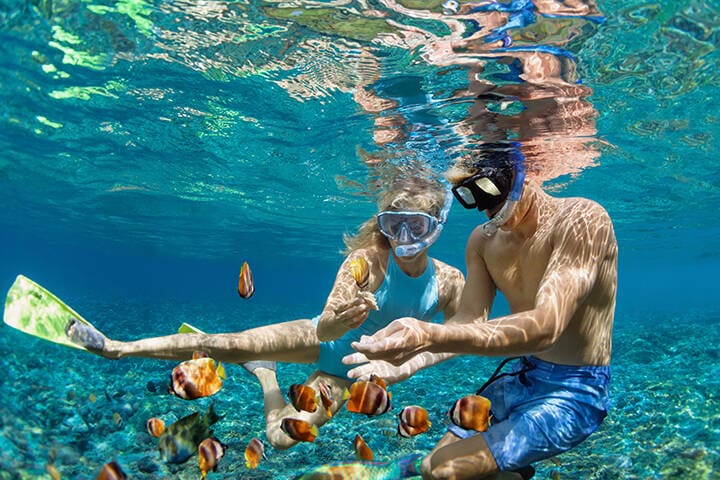 Young couple in snorkeling mask, diving with fish in Bali